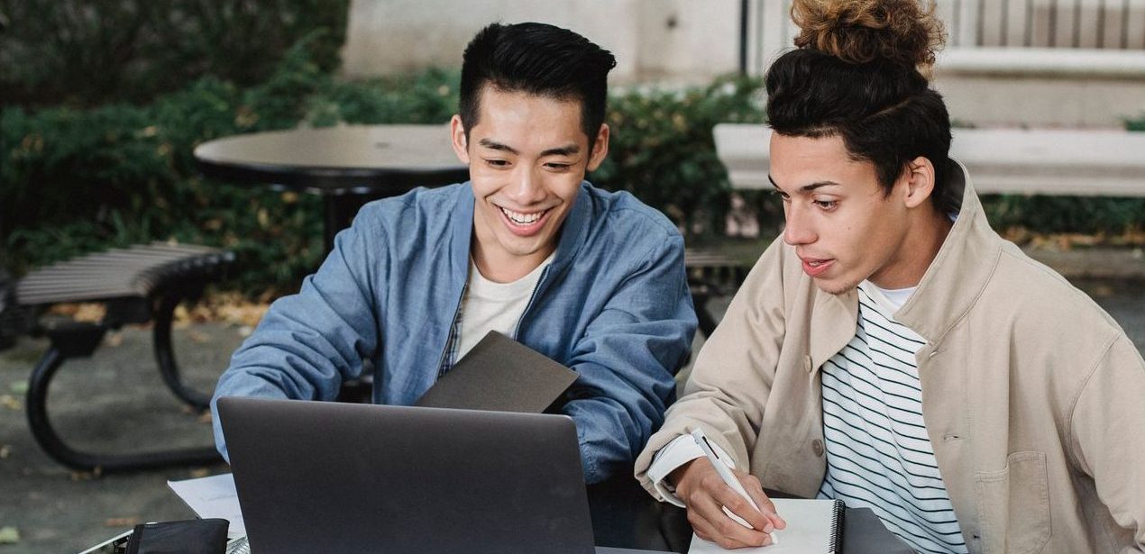 positive multiethnic students using laptop for studies